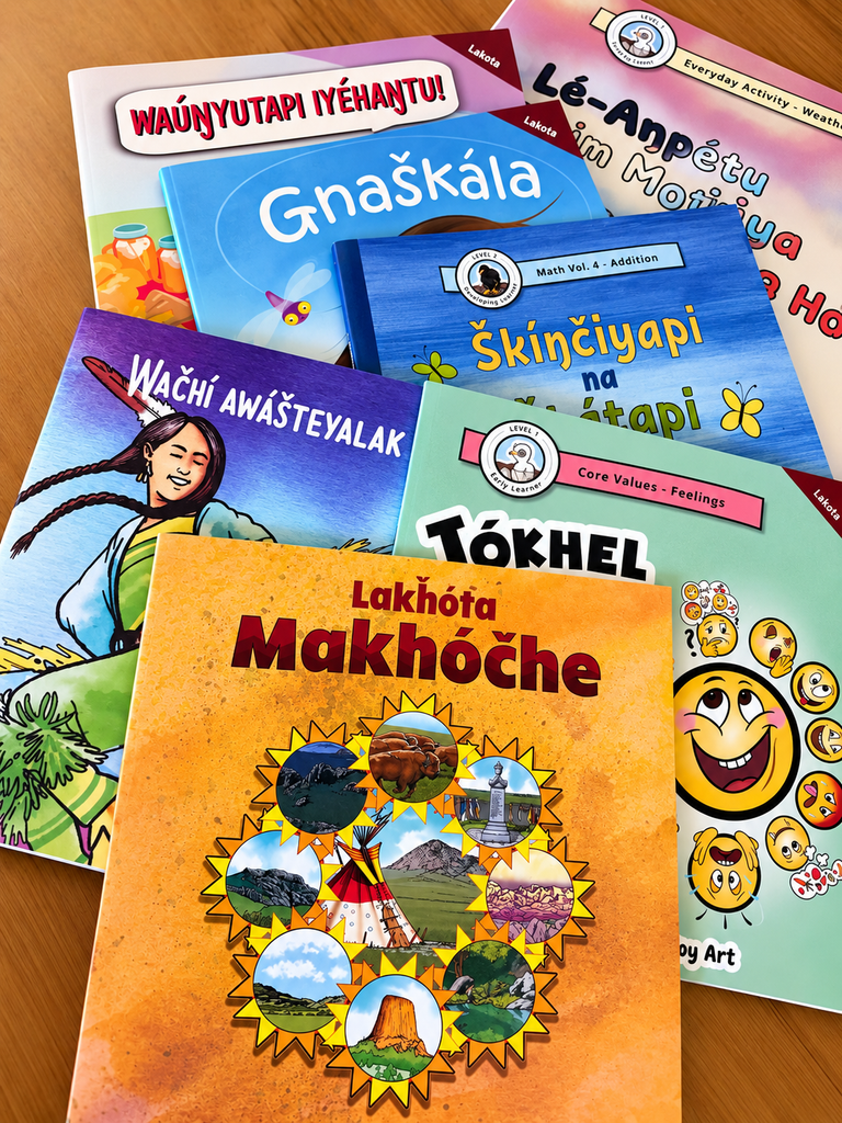 Lakota children’s books displayed together on a wooden surface.